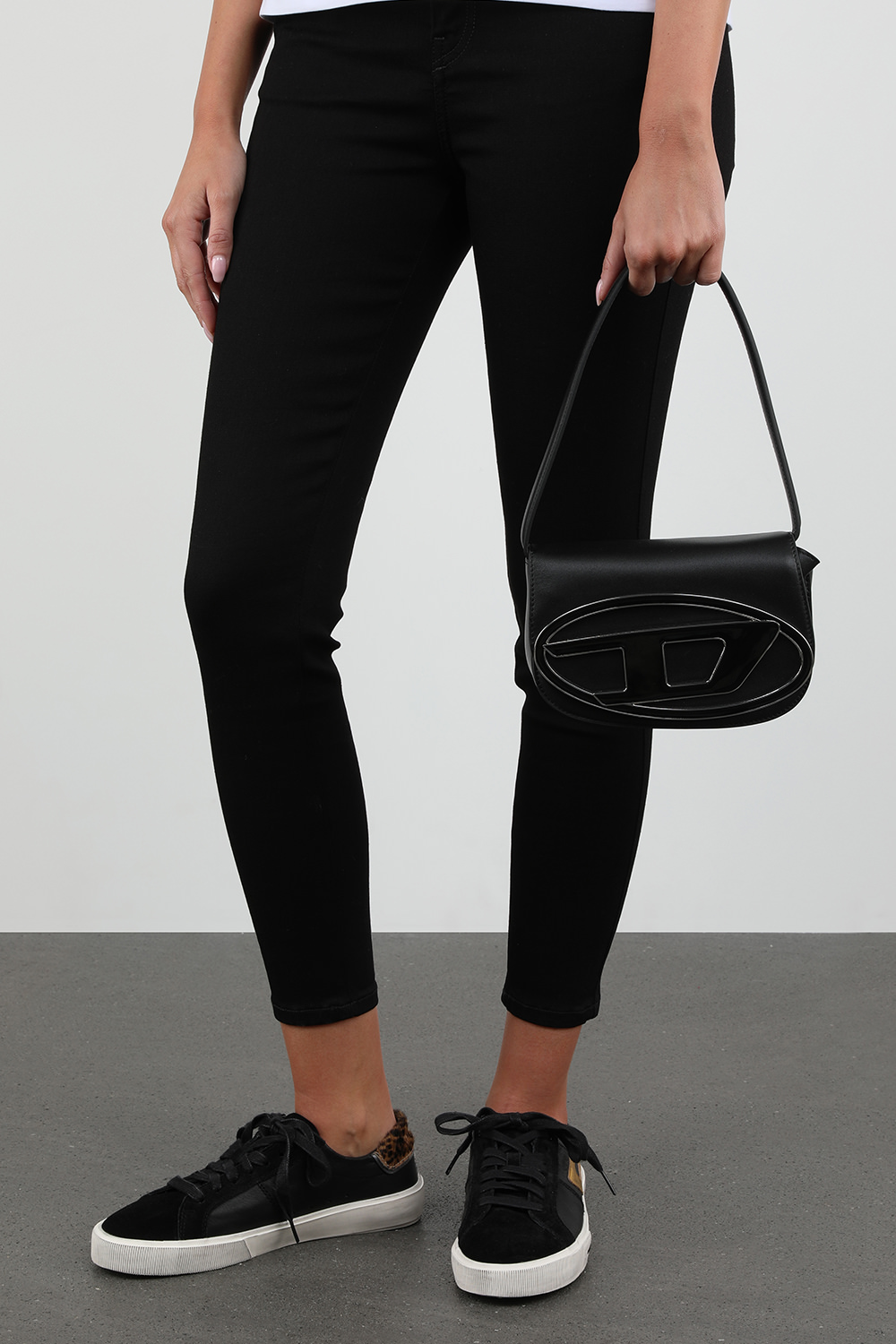 תמונת כל הלוק של תיק כתף מעור שחור עם אלמנט לוגו מטאלי בחזית